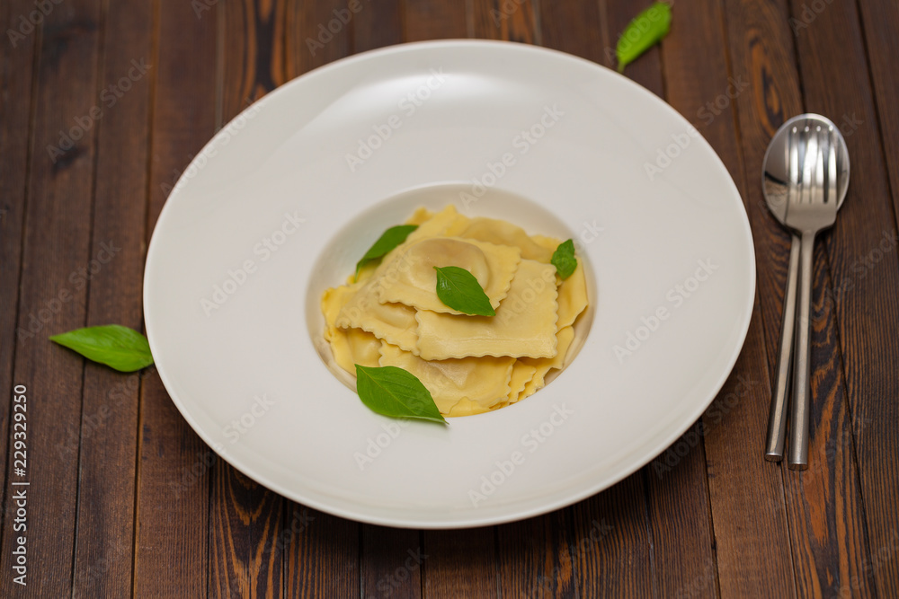 Plate of ravioli with basil on dark background