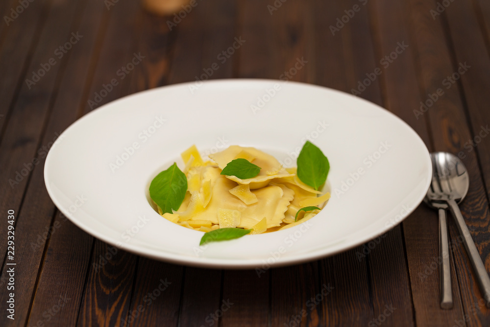 Plate of ravioli with basil on dark background