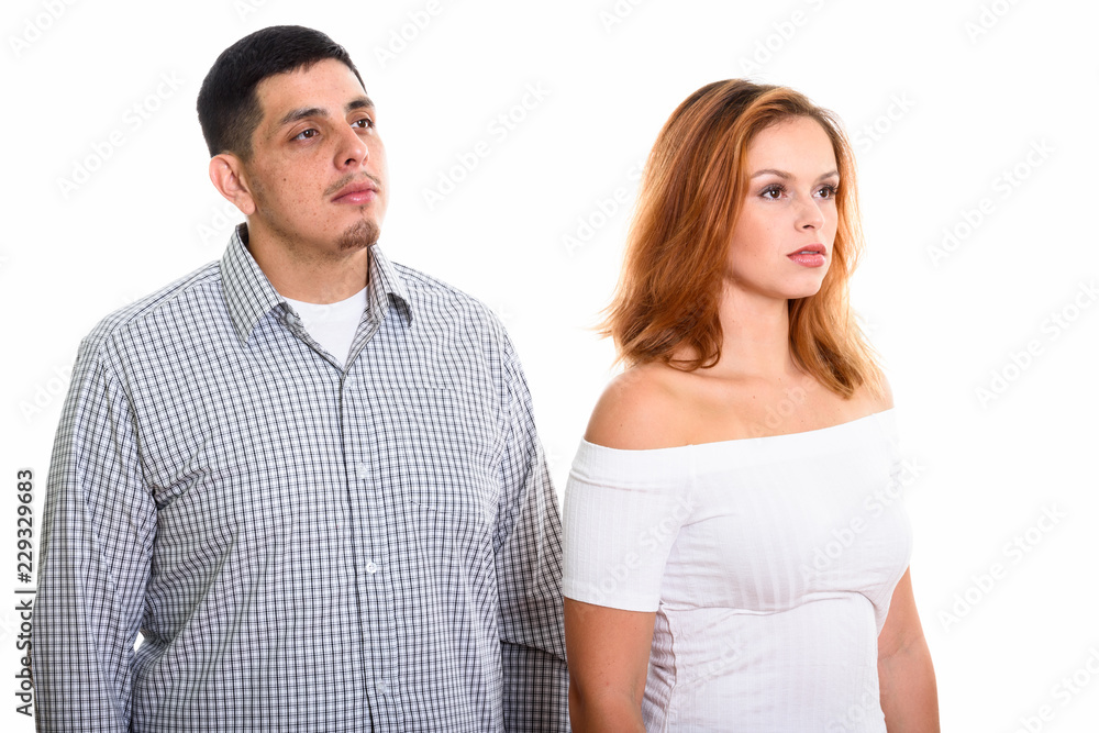 Studio shot of young Hispanic couple thinking while looking away together Studio shot of young Hispanic couple thinking while looking away together