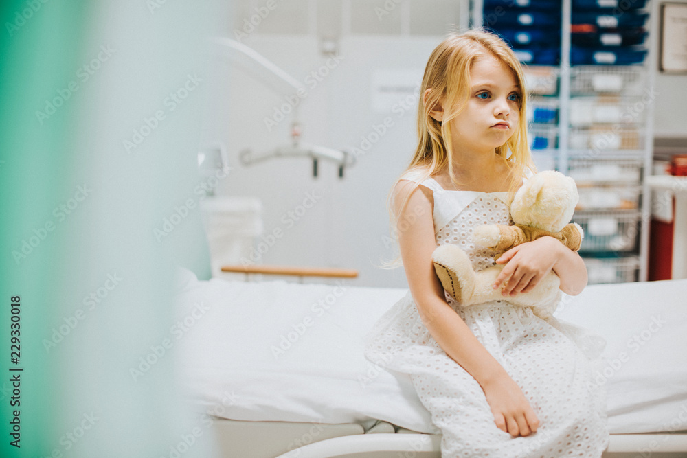 Young girl sitting alone on a hospital bed Young girl sitting alone on a hospital bed