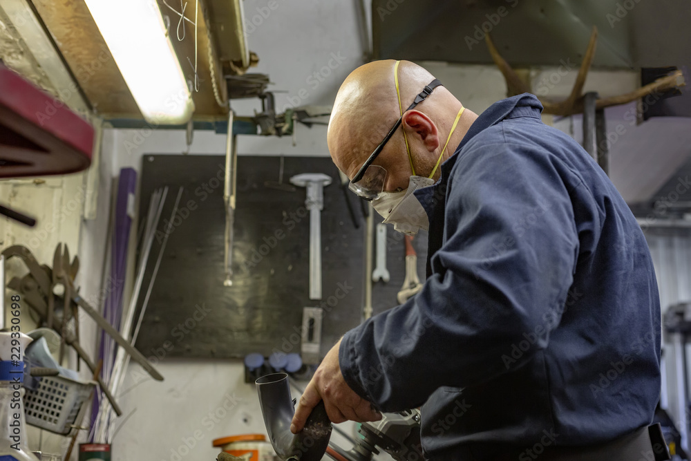 Side view portrait of man working in garage repairing motorcycle and customizing it Side view portrait of man working in garage repairing motorcycle and customizing it