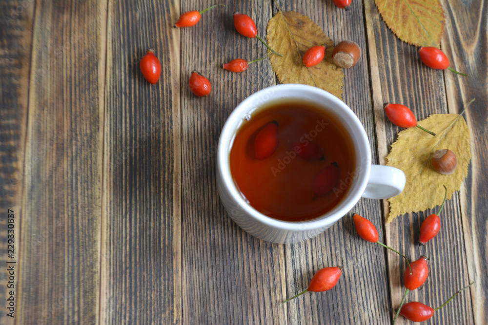 Autumn composition with rose hips nuts leaves a Cup of tea. A Cup of tea with rose hips. Autumn hot drink Autumn composition with rose hips nuts leaves a Cup of tea. A Cup of tea with rose hips. Autumn hot drink