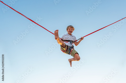 Smilling excited boy jumping on a trampoline with insurance.