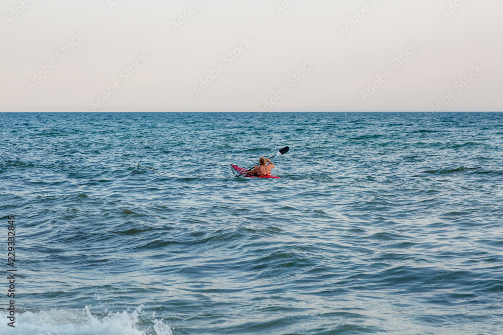 Young woman paddling the sea kayak. Active vacation.