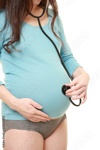 お腹に聴診器をあてて赤ちゃんの心音を聴く水色のシャツを着た臨月の妊婦 Stock Photo Adobe Stock
