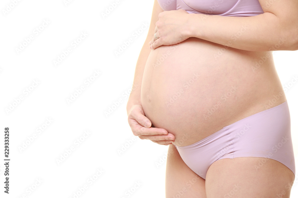 大きくなったお腹を労わる薄紫色の下着を着た臨月の妊婦 大きくなったお腹を労わる薄紫色の下着を着た臨月の妊婦