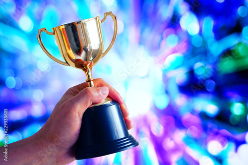 Winner hold trophy with abstract light glowing background photo