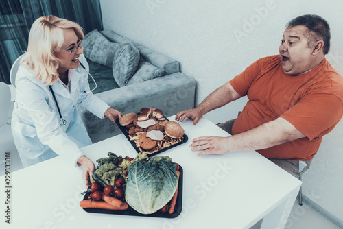 Doctor in White Coat Offers Vegetables to Fat Man. photo