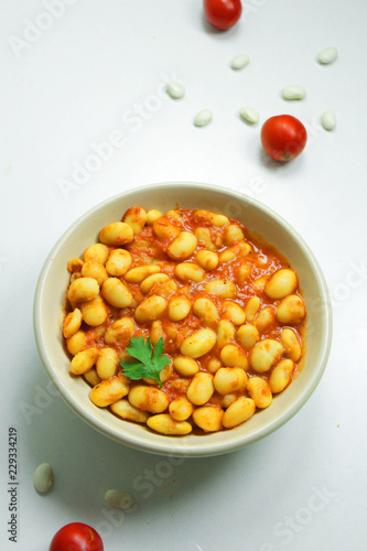 Beans in tomato sauce in a ceramic bowl on a white background