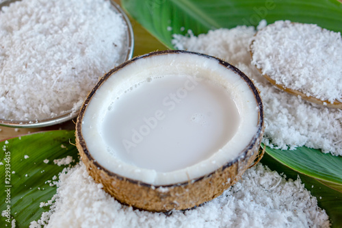 fresh coconut milk in coconut bowl on green leaf background 