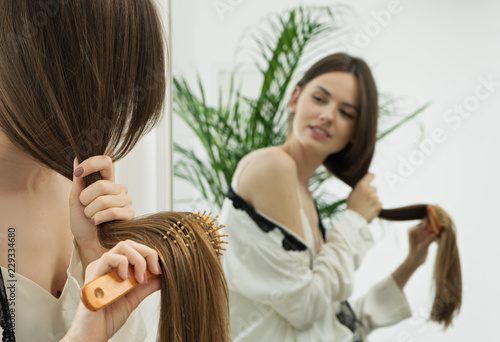 beautiful woman combing her long hair at home