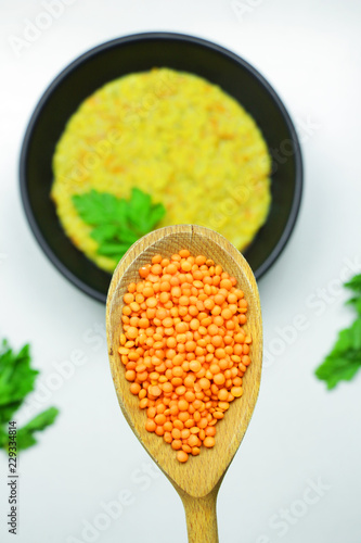 Tasty lentil porridge in a black bowl on a white table