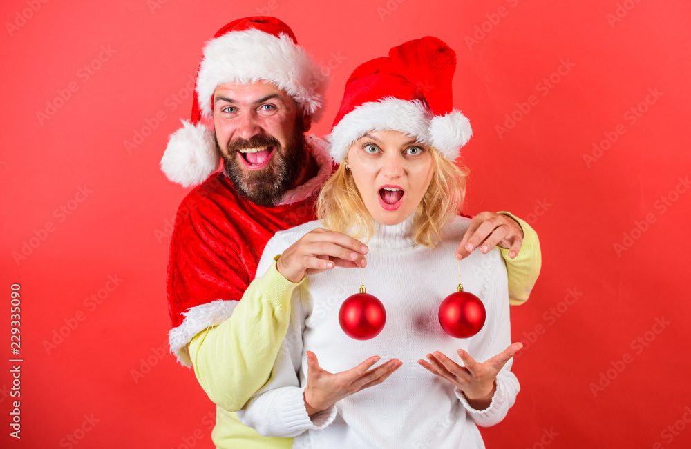 Christmas miracle concept. Plastic surgery. Man santa hat hold balls christmas ornament in front of female breasts. Christmas balls symbol implant female breasts. Couple excited hold christmas balls Christmas miracle concept. Plastic surgery. Man santa hat hold balls christmas ornament in front of female breasts. Christmas balls symbol implant female breasts. Couple excited hold christmas balls