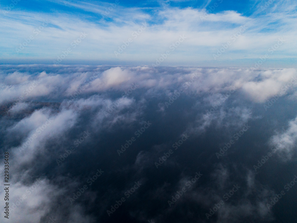 Obraz premium Aerial view White clouds in blue sky. Top view. View from drone. Aerial bird's eye view. Aerial top view cloudscape. Texture of clouds. View from above. Sunrise over the sea