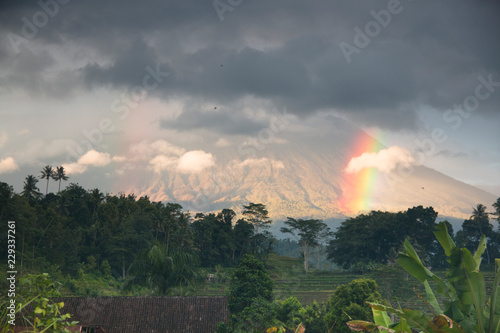 View over the landscape in Sidemen in Bali, Indonesia with Mount Agung volcano and a rainbow in the background 