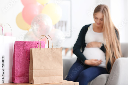 Beautiful pregnant woman with gifts for baby shower party at home