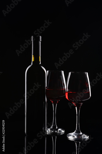 Bottle and glasses of red wine on dark background