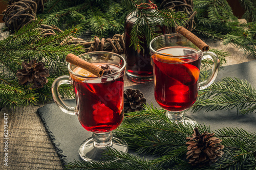 Christmas mulled wine with cinnamon and orange on wooden rustic board. Traditional hot drink at Christmastime.