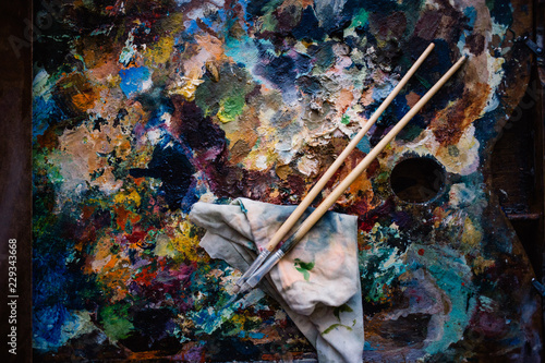 a real artist's palette, oil paints and two paint brushes