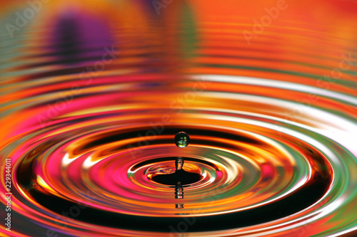 Water drops splash. Red and yellow ripples, reflections on surface