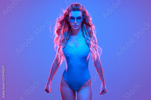 Warrior woman in Pink Blue neon light, Trendy Hairstyle. High Fashion. Sexy adorable long-haired Girl, Stylish Sunglasses. Design Art concept. Creative Colorful Bright Portrait