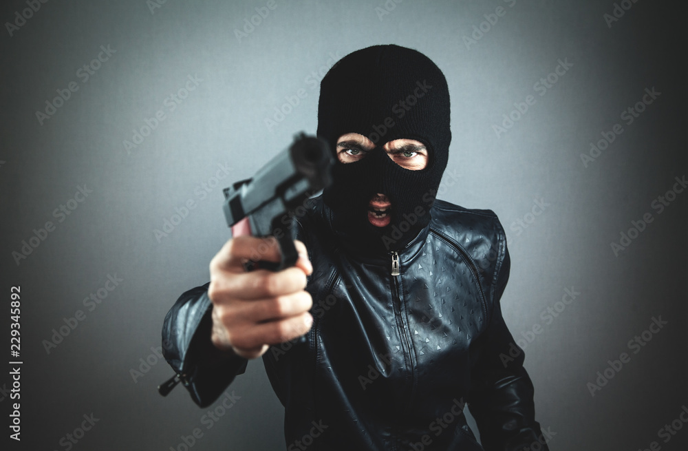 Aggressive man in a black mask with a pistol. Aggressive man in a black mask with a pistol.