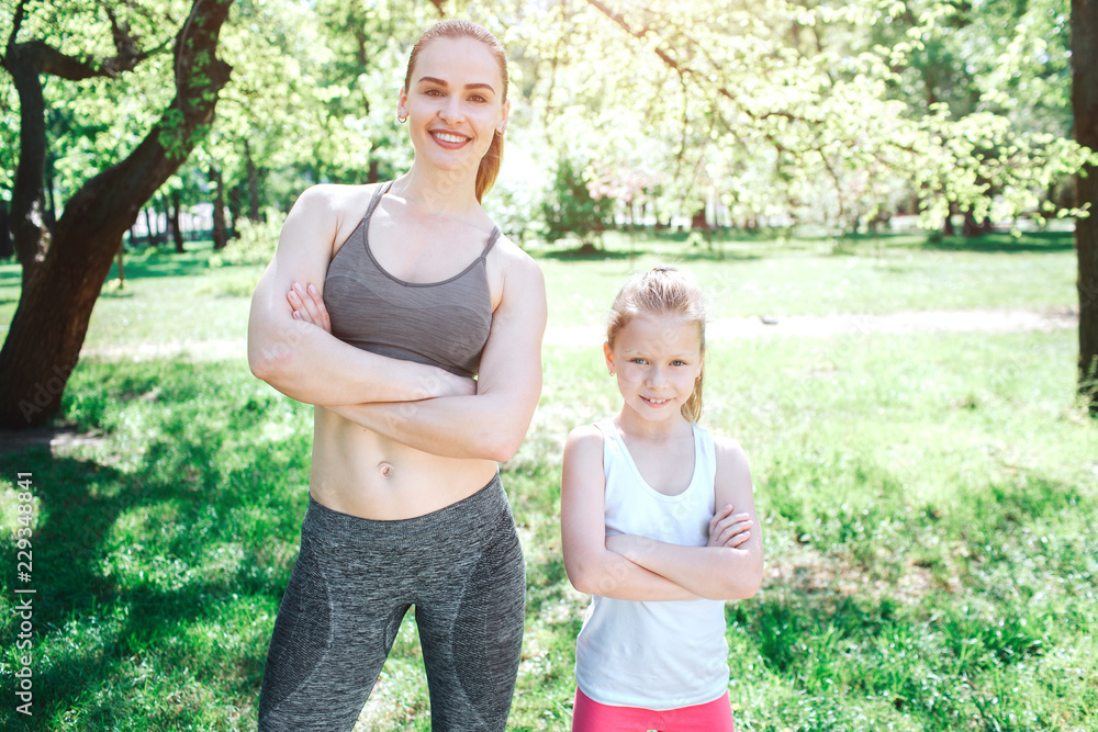 Two confident girls are standing and posing. They are looking straight to camera. Girls are keeping their hands crossed. Yoga and Pilates Concept Two confident girls are standing and posing. They are looking straight to camera. Girls are keeping their hands crossed. Yoga and Pilates Concept