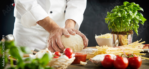 Fototapeta Naklejka Na Ścianę i Meble -  Chef kneading raw dough for an Italian pizza