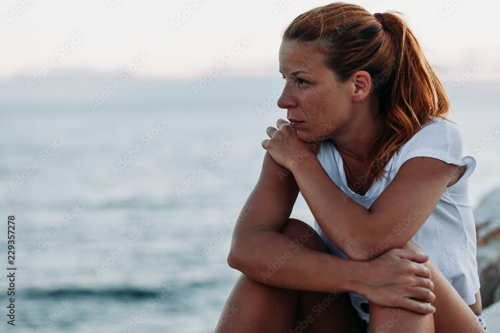 Young woman feeling sad by the sea