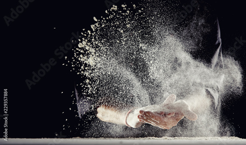 Photographie Flour spraying into air while man wipes his hands