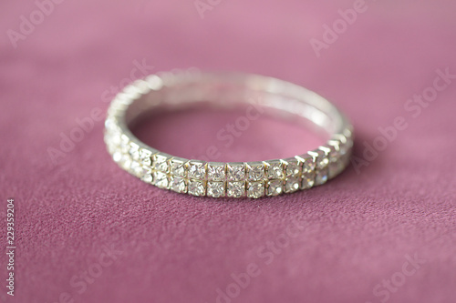 Fake diamonds double row prong setting mount bracelet with selective focus, positioned on a dusky pink suede cloth