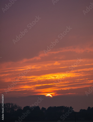 Golden sun touching horizon in sunset