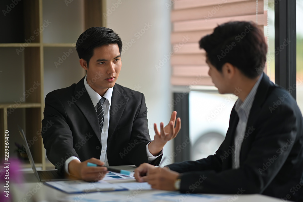 Two Asian colleagues working together on business paper work, laptop in office. Two Asian colleagues working together on business paper work, laptop in office.