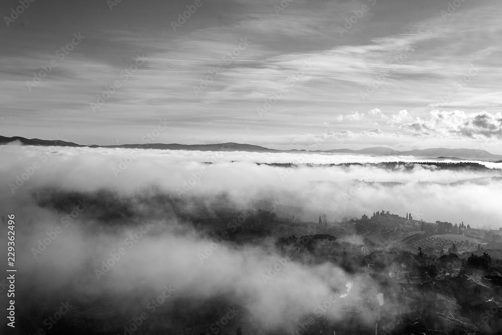 A beautiful view of the hills in Tuscany submerged by a morning mist that gives a magical touch to the scene from the top of one of the towers of San Gimignano