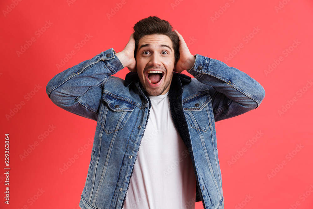 Portrait of an excited young man dressed in denim jacket - obrazy, fototapety, plakaty 