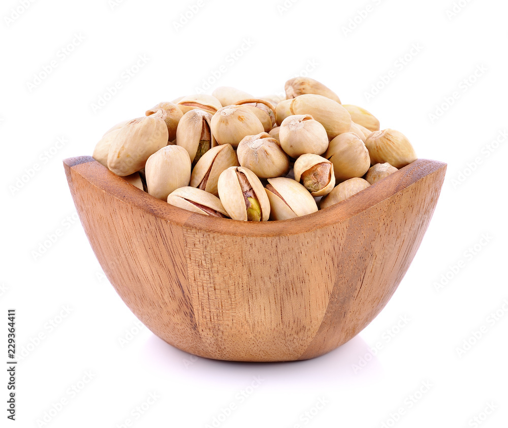 Pistachio nuts in wooden bowl on white background. Pistachio nuts in wooden bowl on white background.