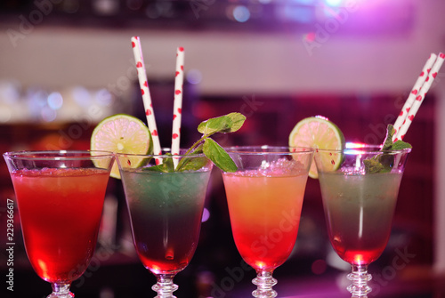beautiful fresh alcoholic cocktails with mixed colored layers on the background of a bar in a nightclub.