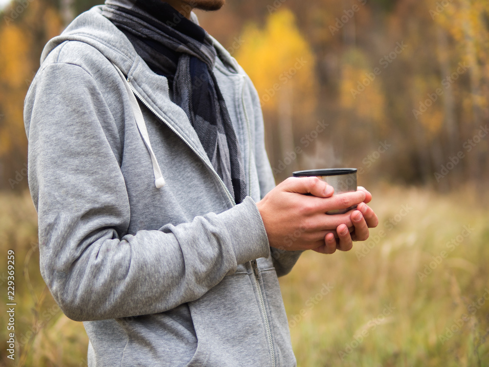 man drinking hot tea from a thermos during a walk through the autumn forest. close-up with copy space man drinking hot tea from a thermos during a walk through the autumn forest. close-up with copy space