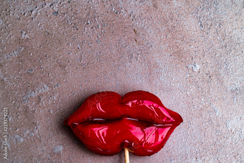 Plastic surgery concept. Cropped close up photo of big red lips candy on grey background photo