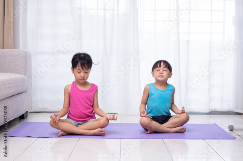 Asian Chinese little sisters practicing yoga pose on a mat