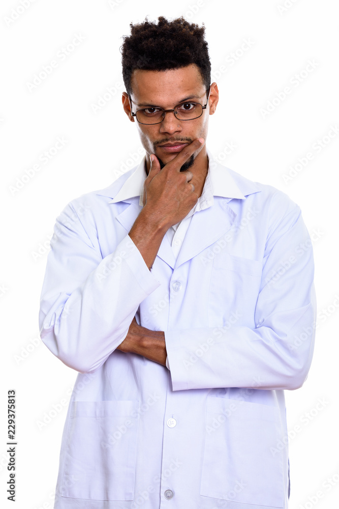 Studio shot of young African man doctor thinking with hand on ch Studio shot of young African man doctor thinking with hand on ch