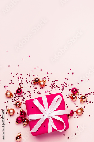 Christmas greeting card with gift and balls confetti on pastel background