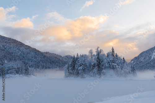 sunset at lake Weitsee in winter with smoke on water