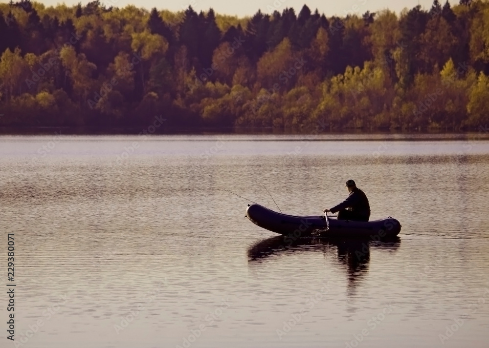 Fisherman catches fish. A man on a fishing trip with fishing rods and a rubber inflatable boat. Fisherman catches fish. A man on a fishing trip with fishing rods and a rubber inflatable boat.