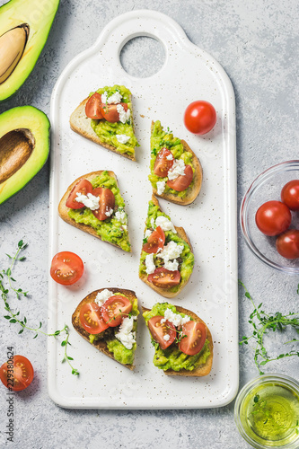 Avocado cherry tomatoes feta cheese toasts on board. Top view, space for text.
