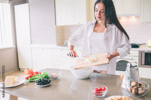 Concentrated girl is cooking breakfst. She is putting cheese into bowl. Girl looks concentrated and thoughtful.
