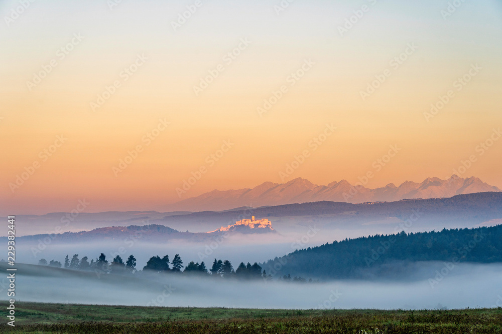 Obraz premium Early morning shot of Spis Castle surrounded with morning fog/mist in autumn time.
