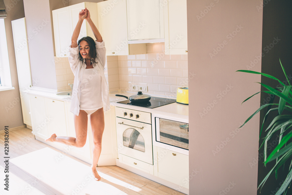 Pretty girl is dancing. She is stretching up and looking down. Girl has some fun. She waits her food to be cooked in pan.