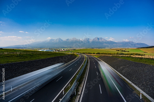 Scenic view of highway leading to rocky peaks of High Tatras mountains, Slovakia summer day.