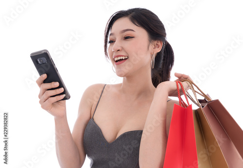 woman using smartphone and holding shopping bags isolated on white background